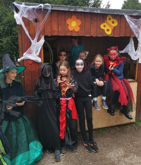 Verkleidete Kinder für Halloween vor einem geschmückten Stand aus Holz